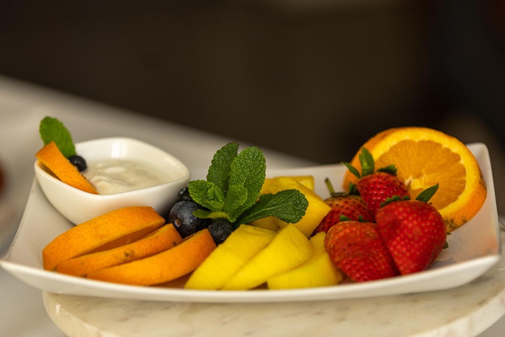 Side angle of fresh fruit platter with mango slices, strawberries and orange segments