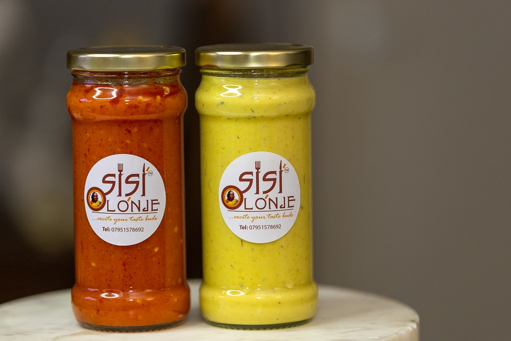 Sisi Olonje Sweet Pepper Sauce and Hot Sauce in branded jars displayed side by side