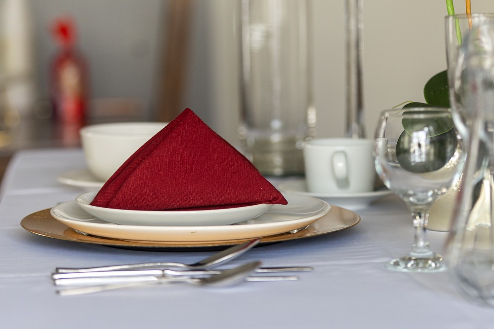 Elegantly set dining table with red napkin and gold charger plate