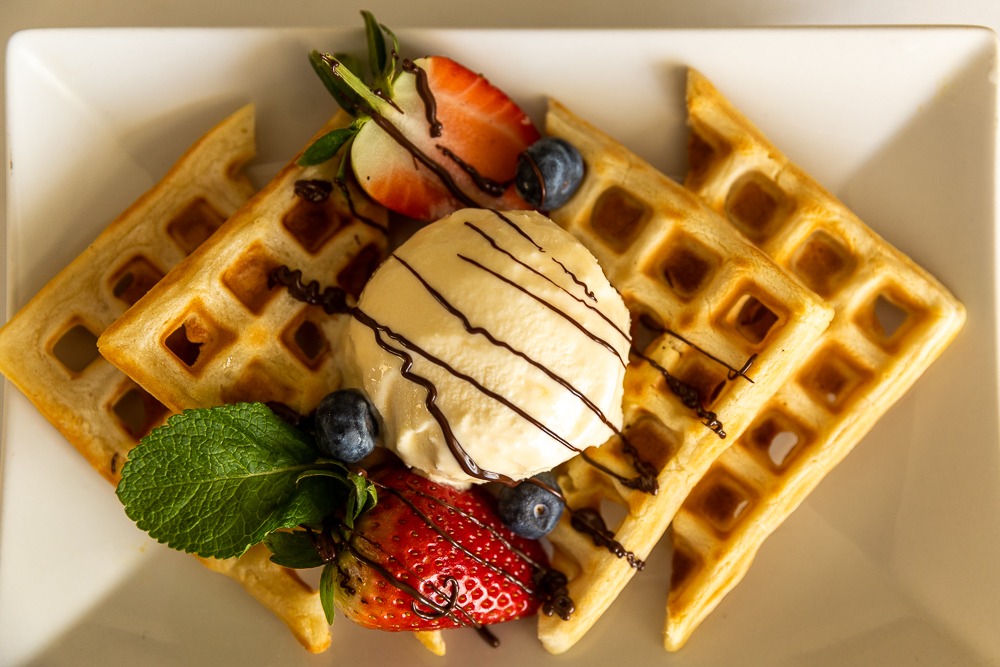 Belgian waffles with ice cream, berries and chocolate drizzle